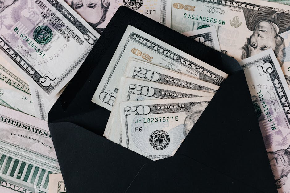 From above of dollar bills in opened black envelope placed on stack of United states cash money as concept of personal i
